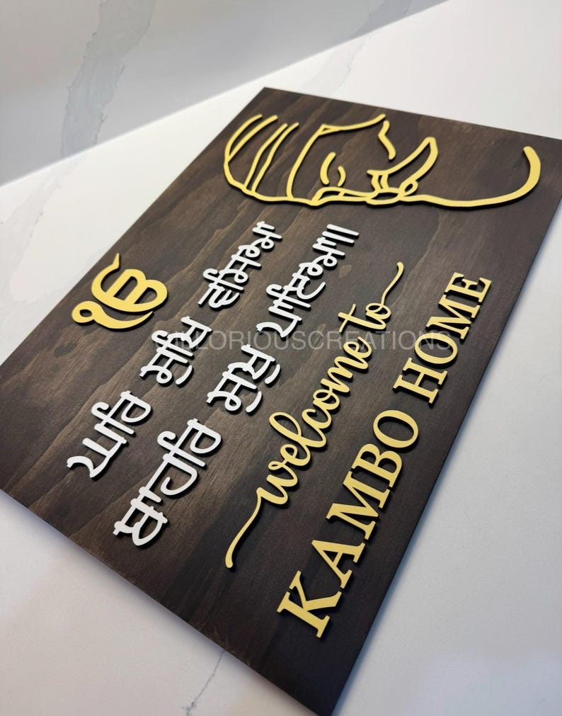 Wooden Gurbani welcome sign showing layered white and gold lettering