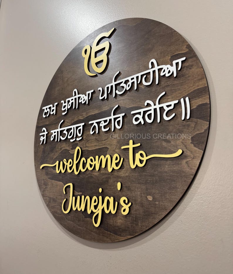 Angled close-up of round Sikh wooden welcome sign with Ik Onkar and Lakh Khushian Patsahiyan Gurbani